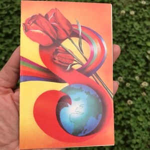 May include: A vintage postcard with a colorful design featuring a rainbow, a globe, and red tulips. The postcard has a yellow background with a red, orange, and yellow swirl.