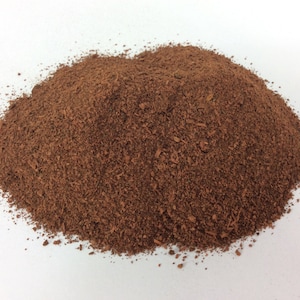 Puede incluir: Un montón de polvo de cacao marrón sobre una superficie blanca.