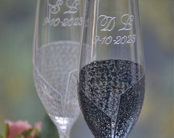 May include: Two champagne flutes with black and white decorative designs. The flutes are engraved with the initials "S L" and "D L" and the date "9-10-2023".
