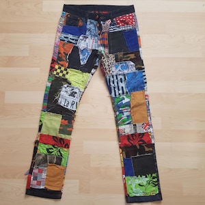 Könnte beinhalten: Hose aus einer Vielzahl bunter Stoffflicken, darunter Tarnmuster, Blumenmuster, Karomuster und einfarbige Textilien. Das Kleidungsstück verfügt über einen Knopfverschluss, einen dunklen Bund und ein Patchwork-Design, auf dem der Text La R zu sehen ist.