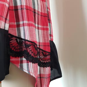 May include: A red and black plaid skirt with a black lace trim. The skirt is asymmetrical and has a black lining.