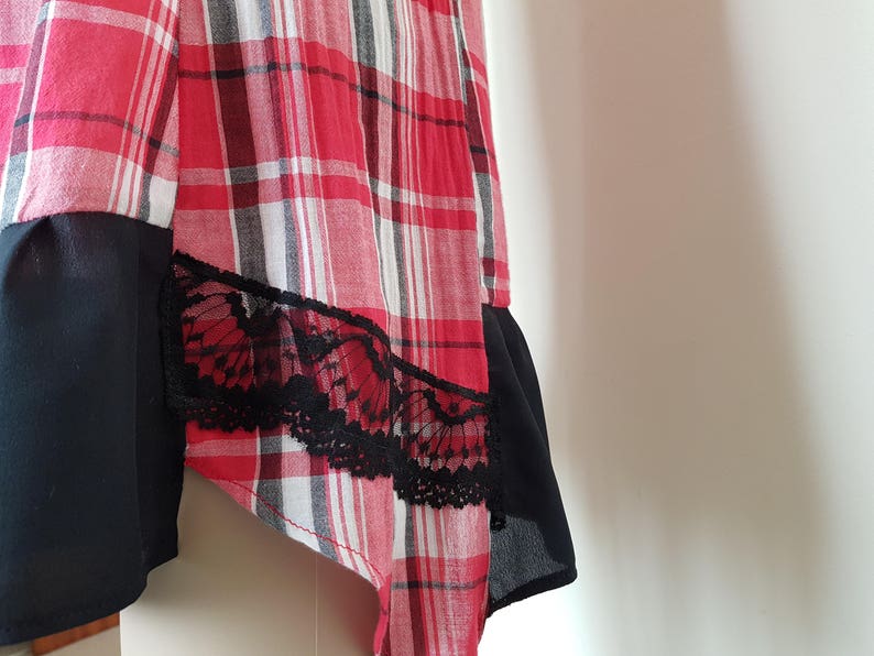 May include: A red and black plaid skirt with a black lace trim. The skirt is asymmetrical and has a black lining.
