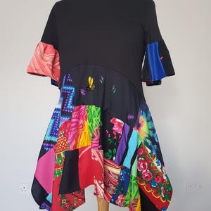 May include: A black short-sleeved dress with a patchwork skirt made of colourful fabrics. The skirt features a variety of patterns, including floral, geometric, and tie-dye. The dress has a unique asymmetrical hemline.