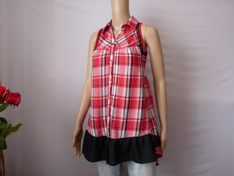 May include: A sleeveless red and white plaid shirt with a black ruffle trim and a black lace detail on the straps.