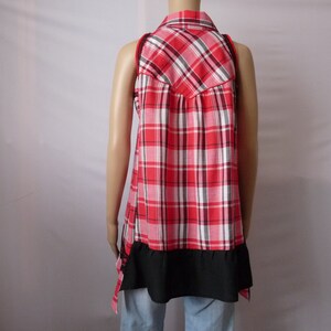 May include: A red and white plaid sleeveless shirt with a black trim and a ruffled hem.