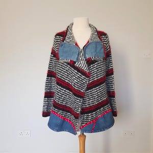 May include: An eye-catching open-front jacket with a distinctive design. The jacket has a black, white, and red striped pattern, denim detailing on the pockets and hem, and a red polka dot trim. The jacket is displayed on a mannequin.