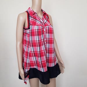May include: A red and white plaid sleeveless shirt with a black lace trim and a black ruffle hem.