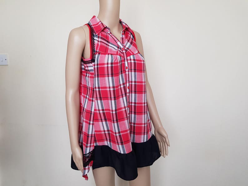 May include: A red and white plaid sleeveless shirt with a black lace trim and a black ruffle hem.