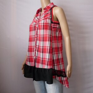 May include: A red and white plaid sleeveless shirt with a black lace trim and a black ruffle at the bottom.
