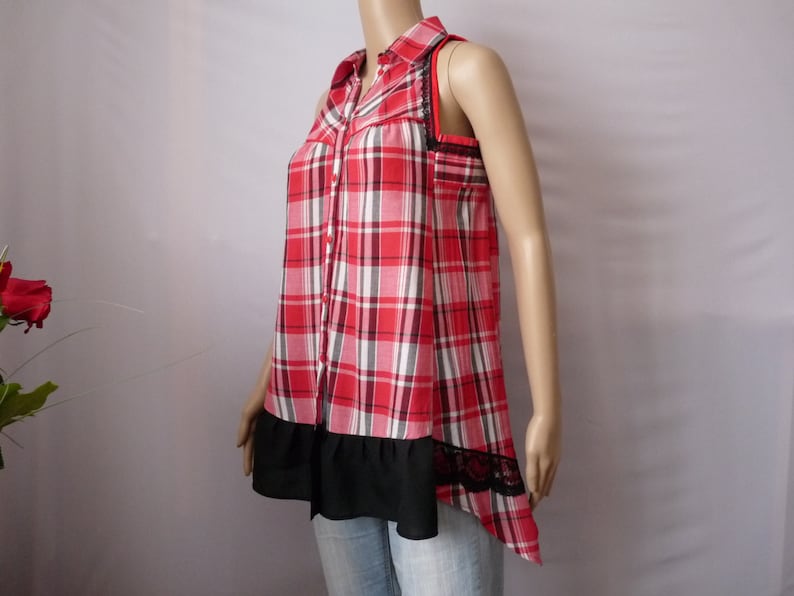 May include: A red and white plaid sleeveless shirt with a black lace trim and a black ruffle at the bottom.