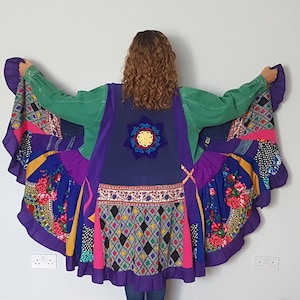 May include: A colourful patchwork jacket with a green denim top and a skirt. The skirt has floral, geometric, and polka dot patterns in blue, purple, pink, and yellow. A crocheted flower is on the back.