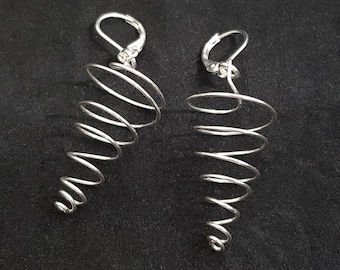 May include: A pair of silver spiral earrings. The earrings are made of a single, continuous piece of wire that is twisted into a spiral shape. The earrings are long and dangle from the ear.
