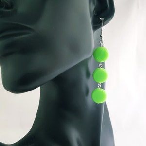 May include: Lime green dangle earrings with three round beads on a silver chain.