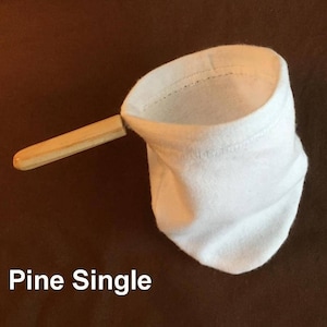 May include: White cotton coffee filter with a wooden handle. The filter is folded and ready to be used. The text "Pine Single" is visible below the filter.