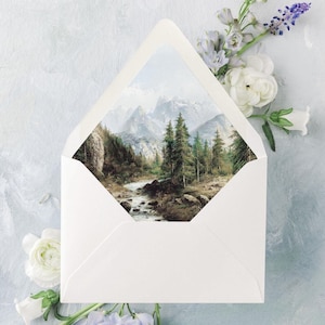 Peut inclure: Une enveloppe blanche avec une peinture de paysage de montagnes et d'arbres. L'enveloppe est ornée de fleurs blanches et violettes sur un fond bleu clair. La peinture à l'intérieur de l'enveloppe représente une rivière traversant une forêt.