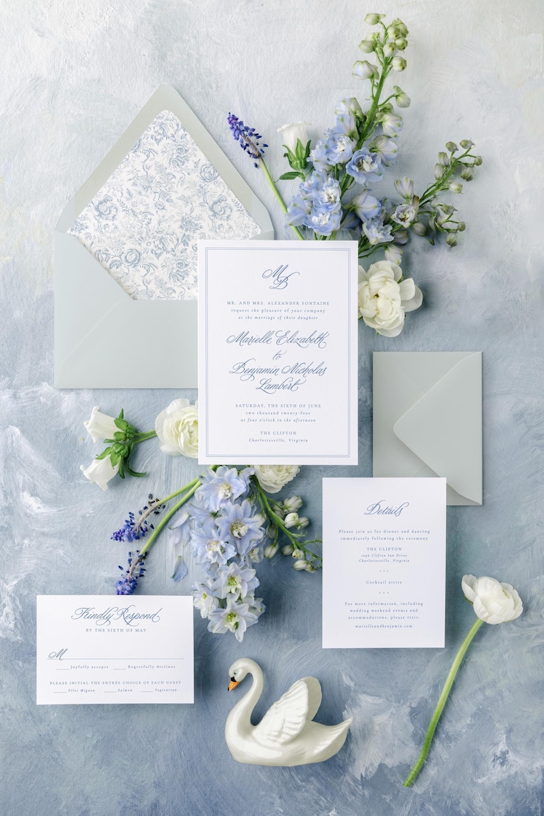 May include: A wedding invitation suite with a blue and white color scheme. The invitation card features a calligraphic font and the text "Mr. and Mrs. Alexander Fontaine request the pleasure of your company at the marriage of their daughter Marielle Elizabeth to Benjamin Nicholas Lambert Saturday, the sixth of June two thousand twenty-four at four o'clock in the afternoon The Clifton Charlottesville, Virginia". The RSVP card features the text "Kindly Respond by the sixth of May".