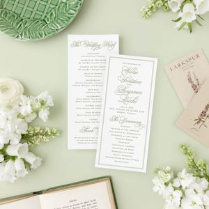a wedding invitation with elegant calligraphy, surrounded by white flowers, a green plate, and a book.
