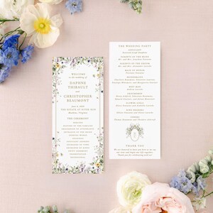 a wedding invitation with a floral border, surrounded by various flowers and greenery.