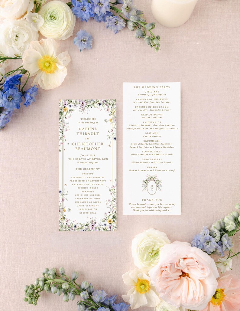 a wedding invitation with a floral border, surrounded by various flowers and greenery.