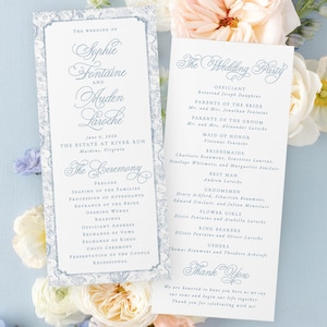 May include: Wedding programs with floral decorations. The programs have a delicate blue script and a floral border, listing the wedding party and ceremony details. The design includes the names of the bride and groom, date, and location.
