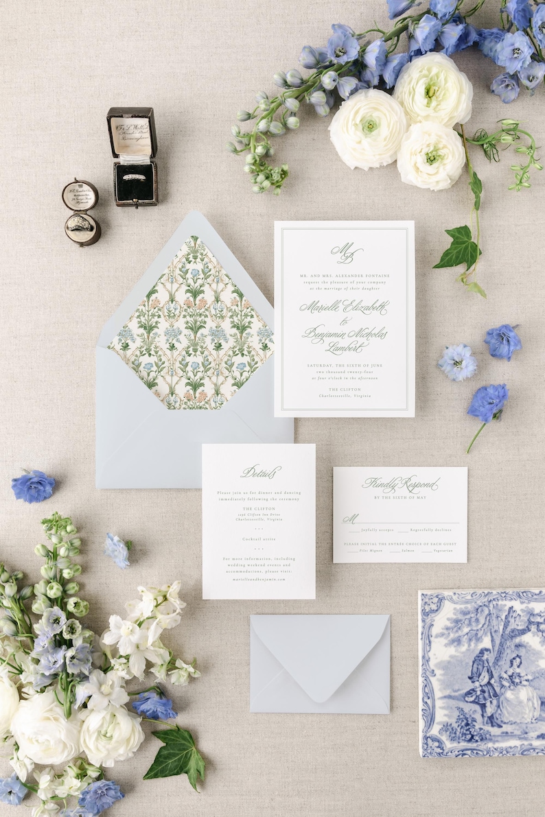 May include: Wedding invitation suite with a blue and white floral design. The invitation features the names "Mardelle Elizabeth" and "Benjamin Nicholas Lambert" and the date "Saturday, the Sixth of June, Two Thousand Twenty-Three". The invitation is on a white background with a blue border. The RSVP card is on a white background with a blue border. The details card is on a white background with a blue border.