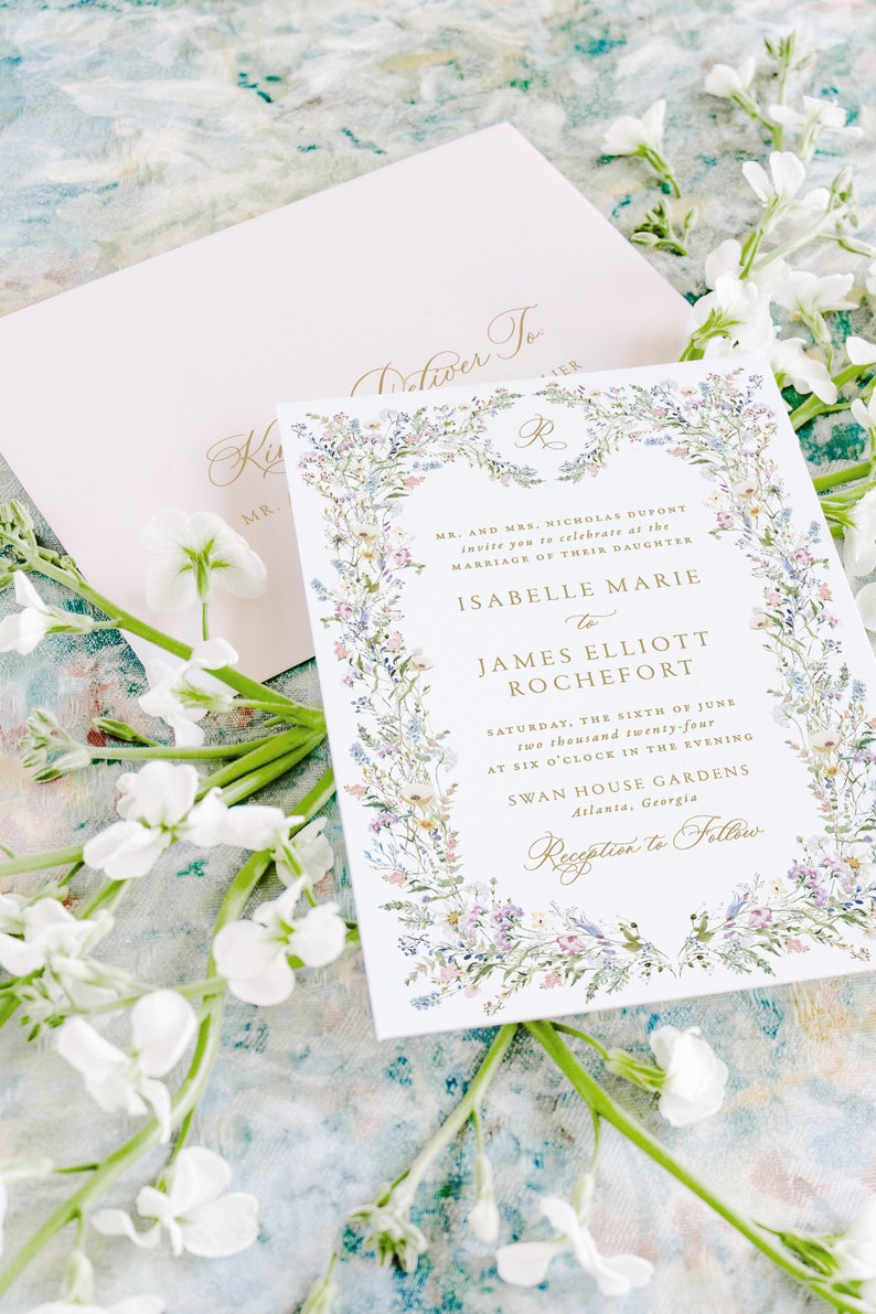 May include: A floral wedding invitation with a gold border and text. The invitation announces the marriage of Isabelle Marie to James Elliott Rochefort on Saturday, June 6, 2024 at 6:00 PM at Swan House Gardens in Atlanta, Georgia. The invitation includes the text "Reception to Follow".
