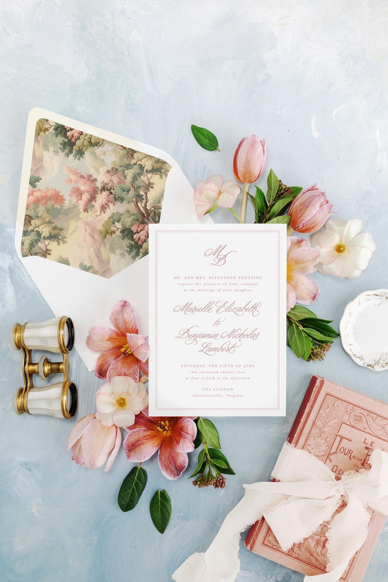 May include: A wedding invitation with pink and white flowers, a vintage book, and a pair of opera glasses. The invitation is for the wedding of Marielle Elizabeth and Benjamin Nicholas Lambert on Saturday, the sixth of June, at four o'clock in the afternoon at The Clifton, Charlottesville, Virginia.