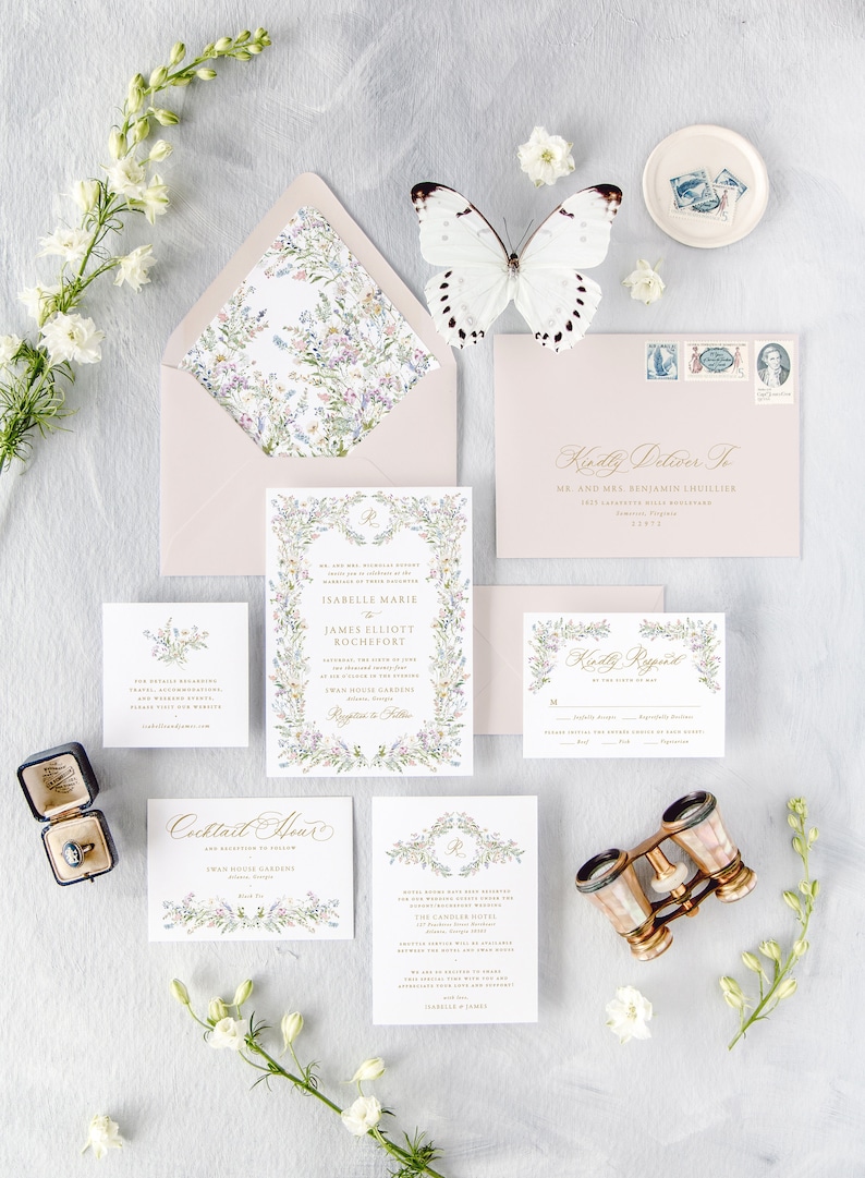 May include: A wedding invitation suite with a floral theme. The invitation features a watercolor illustration of a wreath of flowers and leaves, with the couple's names and wedding date in gold lettering. The RSVP card features a similar floral design, with a space for guests to indicate their attendance. The invitation is accompanied by a pink envelope with a floral pattern.