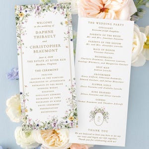 a wedding invitation card with a floral design, surrounded by white and pink flowers.