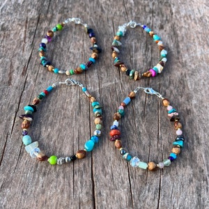 May include: Four colorful beaded bracelets with silver clasps. The bracelets feature a variety of stones, including turquoise, amethyst, and wood.