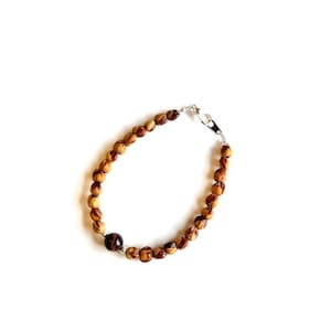 May include: A brown wooden beaded bracelet with a single tiger's eye bead.