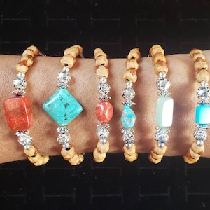 May include: Six bracelets with wooden beads and silver accents. Each bracelet features a different gemstone: turquoise, coral, and green.