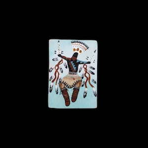 Puede incluir: Una baldosa decorativa rectangular de color azul claro con una figura nativa americana con vestimenta tradicional. La figura tiene los brazos extendidos y está rodeada de plumas y flechas. La figura lleva un tocado y botas.