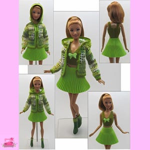 Puede incluir: Una chaqueta con capucha de estampado verde y blanco con una falda plisada verde. La muñeca lleva una blusa verde con un lazo verde. La muñeca lleva botas verdes.