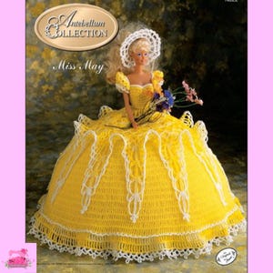 May include: A crochet doll dress in yellow and white with a white lace trim. The dress is designed for a doll with a white bonnet and is part of the "Antebellum Collection" and is called "Miss May".