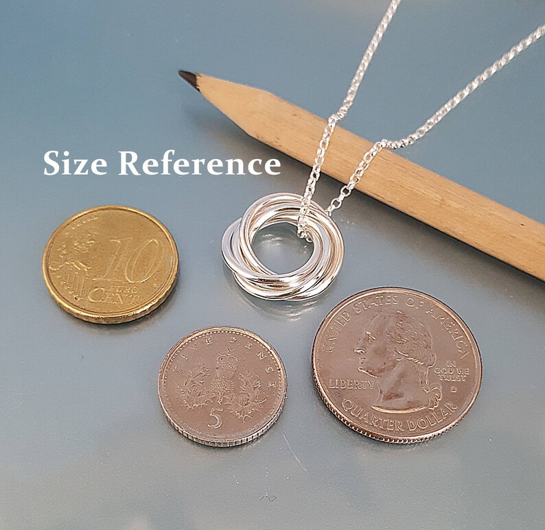 May include: Silver necklace with a five-ring knot pendant. The pendant is about the size of a US quarter. Size reference is shown with US coins.