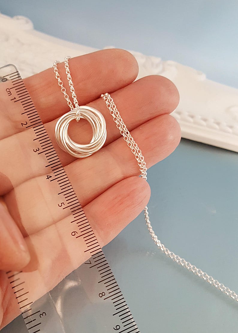 May include: A silver necklace with a circular pendant made of multiple intertwined rings. The necklace is 18 inches long.