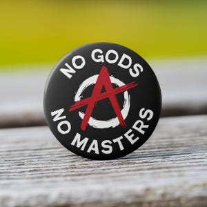 May include: Black and white button with the text "No Gods No Masters" and a red anarchy symbol.