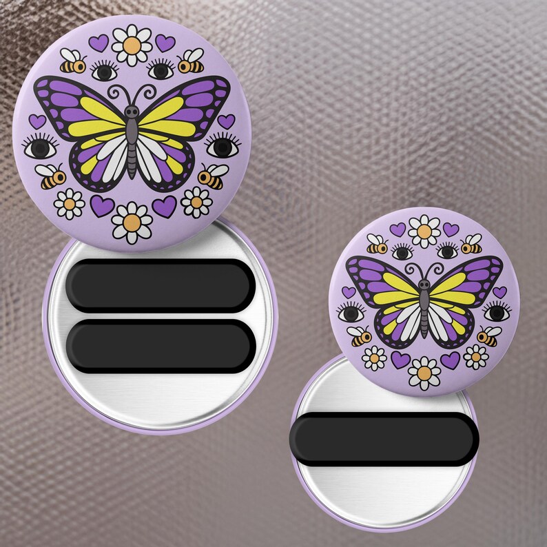 K&ouml;nnte beinhalten: Zwei runde, lavendelfarbene Magnet-Badge-Rollen mit einem Schmetterlingsdesign. Der Schmetterling hat gelbe und lila Fl&uuml;gel, umgeben von Bienen, Augen, Herzen und Blumen. Die Rollen haben einen schwarzen rechteckigen Bereich.