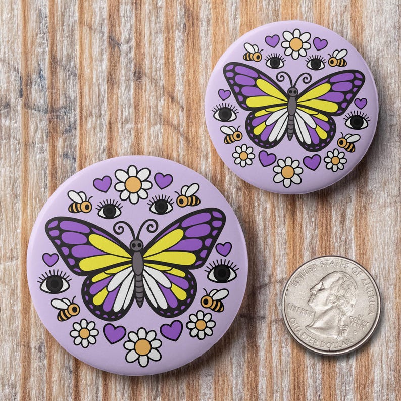 K&ouml;nnte beinhalten: Zwei runde, lila Kn&ouml;pfe mit Schmetterling-, Bienen-, Augen-, Herz- und Blumenmotiven. Der Schmetterling hat lila und gelbe Fl&uuml;gel. Eine amerikanische Vierteldollarm&uuml;nze liegt neben den Kn&ouml;pfen zum Gr&ouml;&szlig;envergleich. Die Kn&ouml;pfe liegen auf einer Holzoberfl&auml;che.