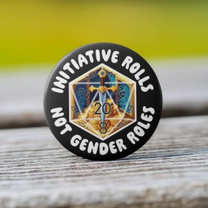 May include: A black and white button with the text "Initiative Rolls Not Gender Roles" and a 20-sided die with a sword and gold coins.