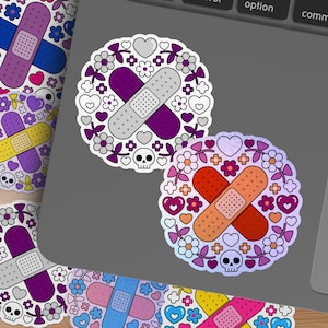 May include: A collection of colorful stickers featuring a bandage design. The stickers are decorated with floral and heart patterns, and a skull. The bandages are in various colors, including purple, orange, and blue.