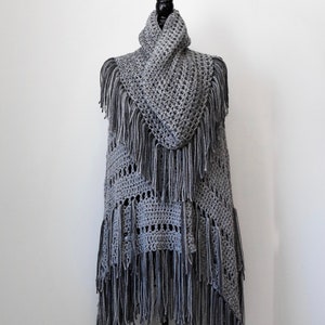 Może przedstawiać: Szary, dziany bezrękawnik z frędzlami. Bezrękawnik jest bez rękawów i ma wysoki kołnierz. Jest prezentowany na manekinie.