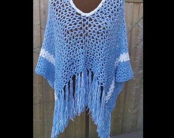 Puede incluir: Un poncho de crochet azul claro con ribetes y flecos blancos. El poncho está en un maniquí.