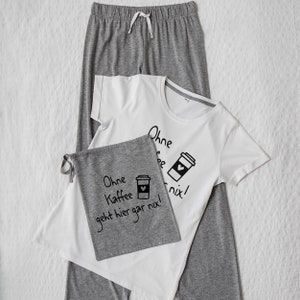 Może przedstawiać: Szara i biała piżama z grafiką kubka z kawą i tekstem "Ohne Kaffee geht hier gar nix!" nadrukowanym na koszulce.
