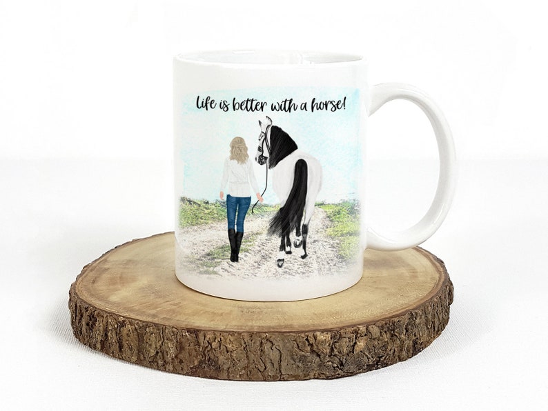 May include: White ceramic mug with a black handle. The mug features a colorful illustration of a woman walking a horse with the text "Life is better with a horse!" printed on the mug.