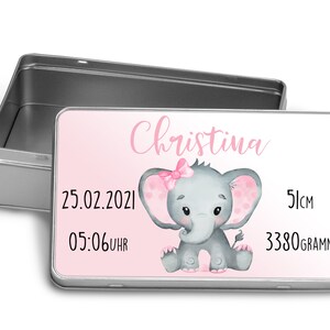 Könnte beinhalten: Eine silberne Metall-Erinnerungskiste mit einem rosa-weißen Design. Die Box zeigt einen Cartoon-Elefanten mit einer rosa Schleife, den Namen Christina, das Datum 25.02.2021, die Uhrzeit 05:06 Uhr, die Messung 51 cm und das Gewicht 3380 Gramm.