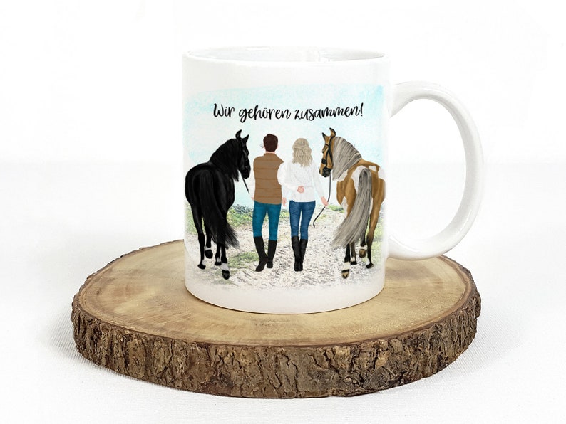 May include: White ceramic mug with a colorful illustration of a couple walking with their horses. The text "Wir geh&ouml;ren zusammen!" is printed on the mug.