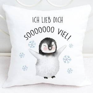 May include: White cushion featuring a charming penguin illustration and the text "Ich lieb dich sooooooo viel!" in black. The penguin is surrounded by blue snowflakes.