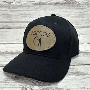 May include: Black baseball cap with a brown leather patch featuring the name "James" and a golfer silhouette.